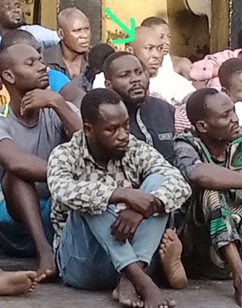 Seun Kuti sitting together with Detained prisoners on the ground 